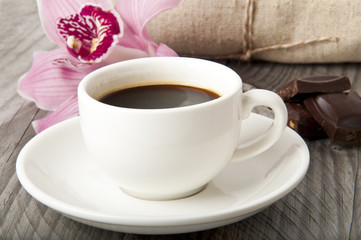 cup of coffee, chocolate and orchid on wooden background
