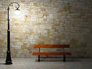 Illuminated brick wall with old street light and bench