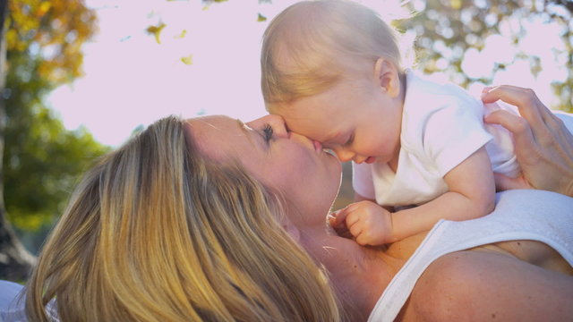 Young Mom Outdoors Tenderly Kissing her Baby