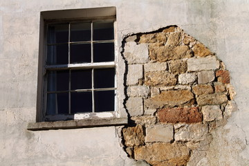Old sash window and wall with missing render.