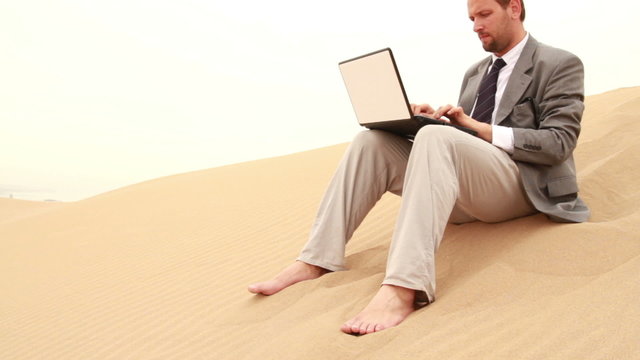 Businessman working on laptop in the desert