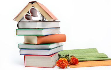 A stack of books and antique clock on a white background.