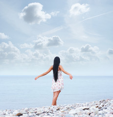 A young woman in a beautiful dress walking near the sea