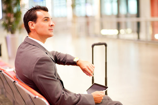 businessman checking time and using tablet at airport