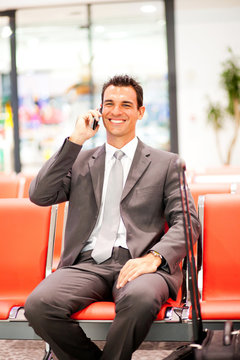 happy young businessman talking on mobile phone at airport