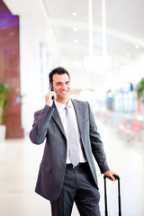 happy young businessman talking on cell phone at airport