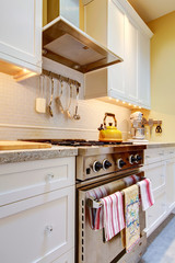 Yellow kitchen with white cabinets and stove.
