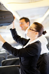 friendly flight attendant helping passenger with luggage