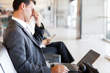 tired businessman taking a break at airport