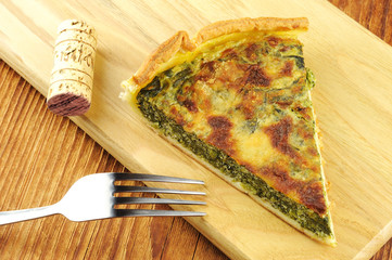 Slice of spinach tart with parmesan - wooden background