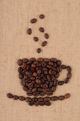 A cup of coffee beans with smoke on the background of burlap.