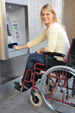 Rollstuhlfahrerin vor Geldautomat