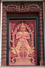 Giant wood sculpture on the door in Thai pagoda .