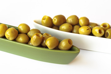 Green olives in two ceramic bowls on white background