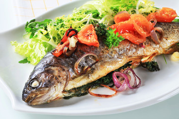 Fototapeta na wymiar Baked trout with tomatoes and green salad