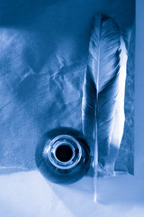 Feather and ink bottle on paper background
