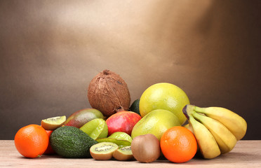 Assortment of exotic fruits on wooden table on brown background