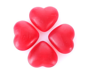 Obraz premium Four red heart-shaped candies arranged in a clover shape, love, romance, and sweetness on a white background
