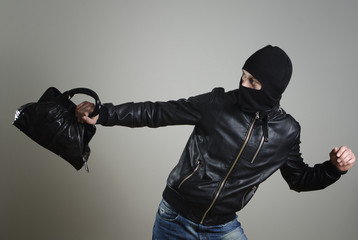 Portrait of running male burglar with a handbag.