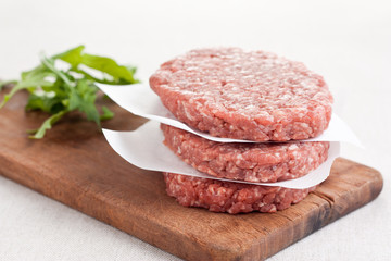 Raw burgers stacked with salad