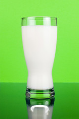 Glass of fresh milk on a dark green background