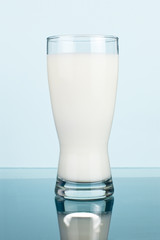 Glass of fresh milk on a dark cyan background