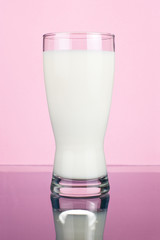 Glass of fresh milk on a dark pink background