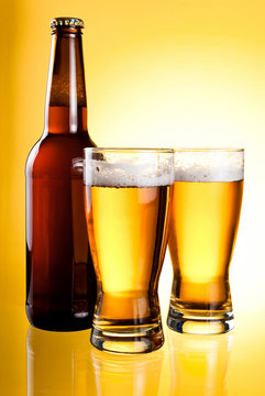 Two glasses and Bottle of fresh light beer on yellow background