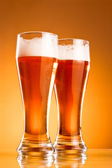 Two glass of beer over yellow background