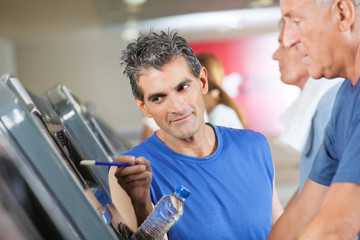 Fitnesstrainer erklärt Mann Laufband