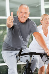 Senior im Fitnesscenter hält Daumen hoch