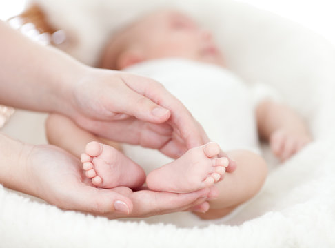 mother's hands holding small baby's feet