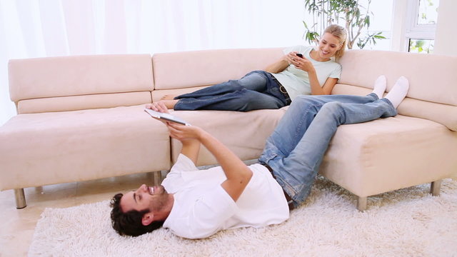 Man lying on a carpet while his girlfriend is on the couch