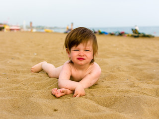 toddler girl laying on the sand beach
