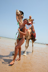Young beautiful woman rolls the children on a camel