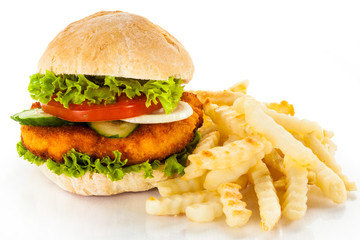 Big hamburger, French fries and vegetables on white background