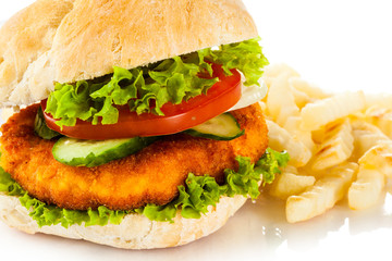 Big hamburger, French fries and vegetables on white background