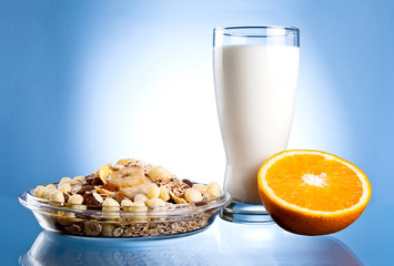 Dish of muesli, glass of fresh milk and Half of juicy orange on