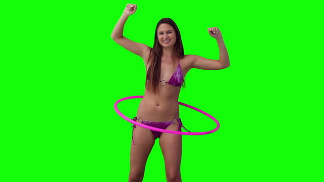 Woman spinning a hula hoop with her arms raised