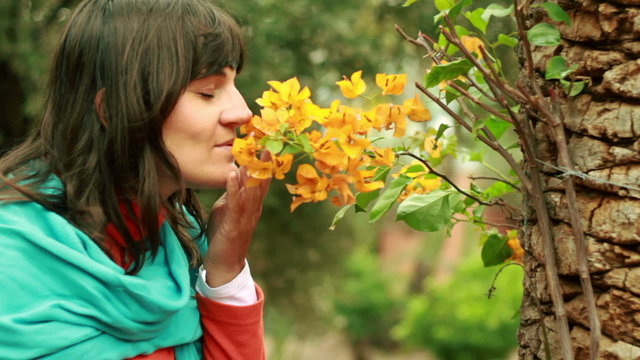 Young woman smelling flowers in the park, steadicam shot