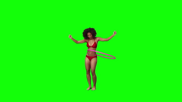 A woman wearing a bikini is using a hula hoop
