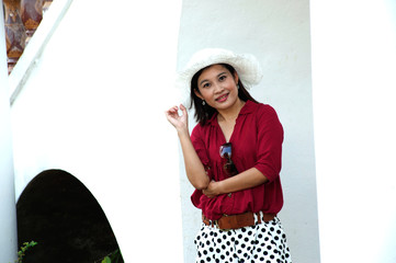 Pretty Asian woman in red dress and white hat .