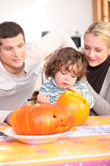 Fototapeta na wymiar Parents and daughter in the kitchen preparing pumpkin