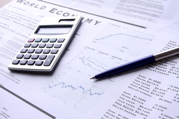 A calculator and a pen over documents, closeup