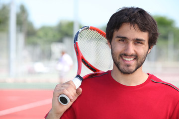 Tennis player stood with racket over shoulder