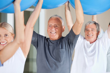 Senioren machen Rückenübungen mit Gymnastikball