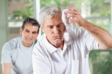 Senior wischt Schweiß von Stirn