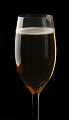 A glass of sparkling champagne on black background