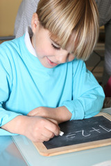 Little boy writing on a slate