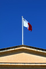 Flag of Malta against blue sky during wind